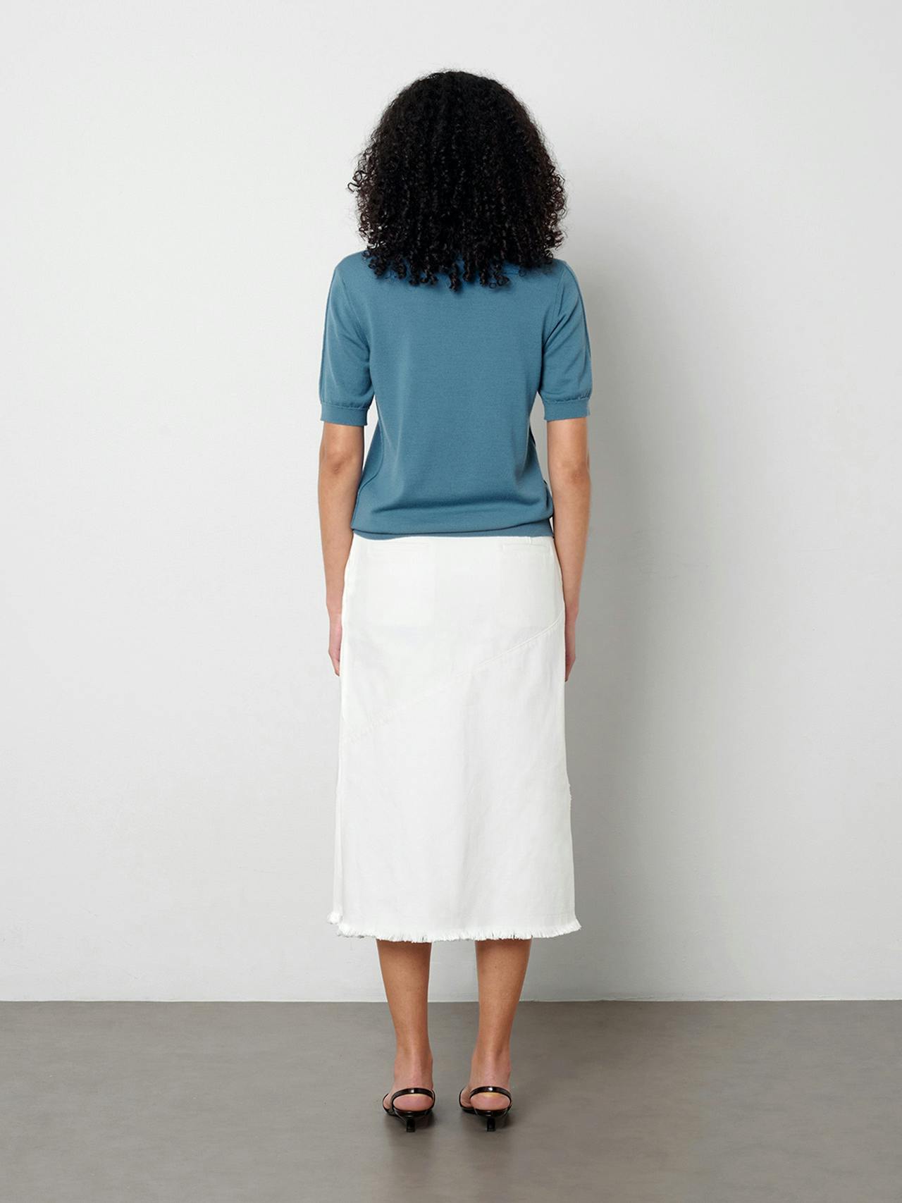 The Uma skirt softly skims the body and falls just below the knee. The crisp white denim is finished with a frayed edge detail at the waist and hem.