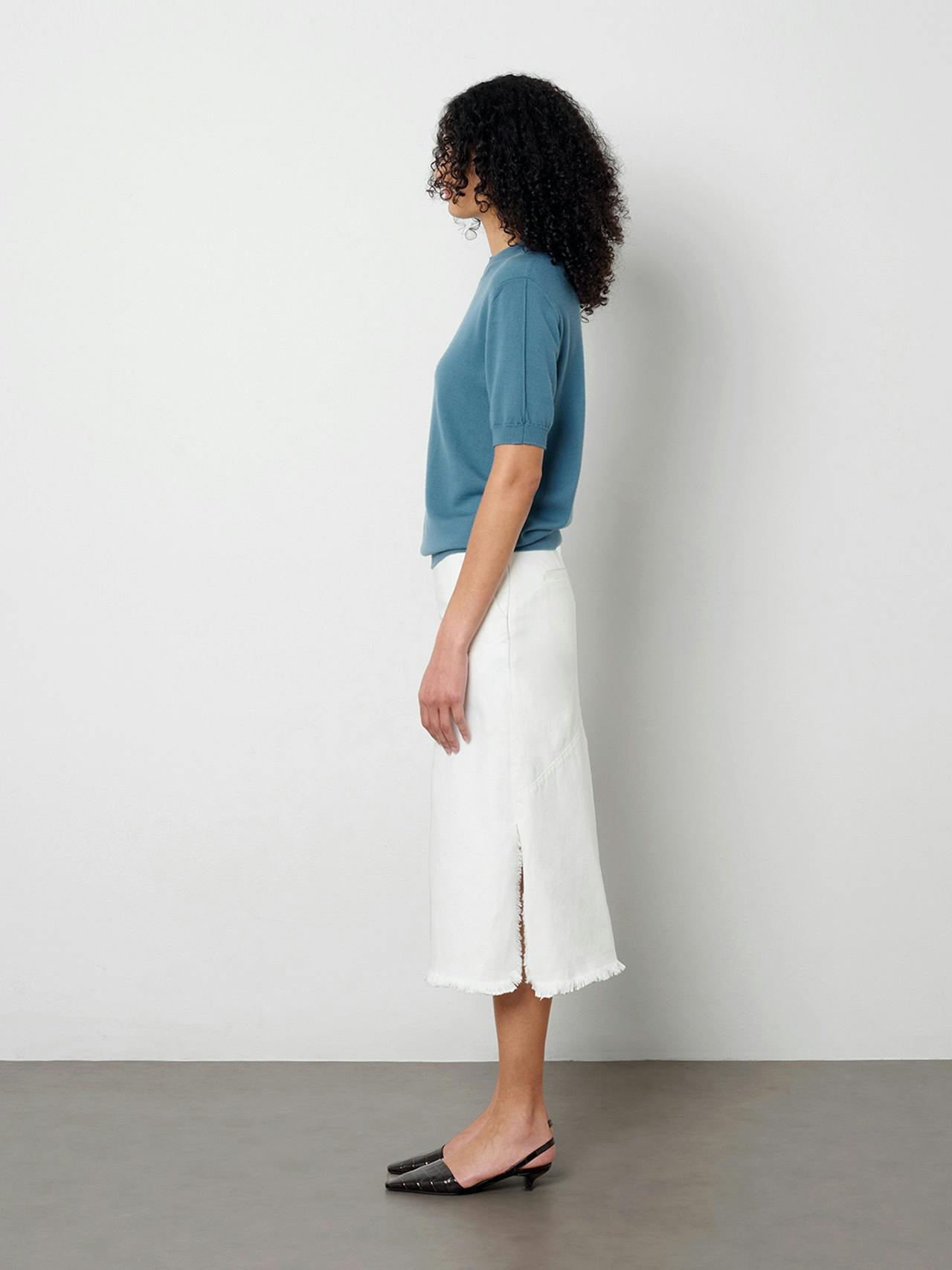 The Uma skirt softly skims the body and falls just below the knee. The crisp white denim is finished with a frayed edge detail at the waist and hem.
